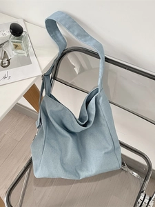 Light blue tie-dye canvas tote bag with adjustable shoulder strap on a chair