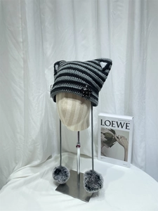 Detail of black and gray striped cat ear beanie with star pins and plush pompom pendants