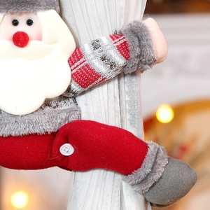 Close-up of Santa Claus plush curtain tieback on white sheer fabric with bokeh lights