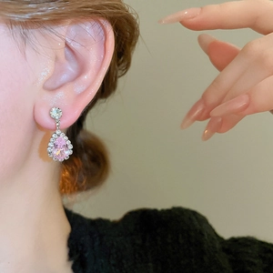 Close-up of pink pear-cut waterdrop earrings set with white diamonds on a model
