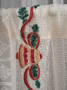 Close-up of American Christmas lace curtain showing red and green bell embroidery detail