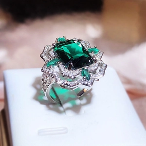 Macro shot of silver ring featuring rectangle green gemstone and sparkling diamond halo