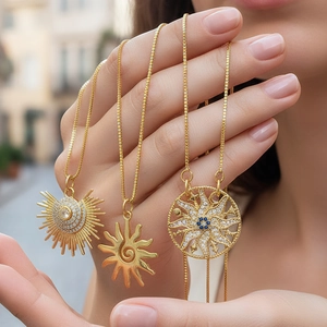 Gold sun necklaces with zircon pavé held by hand, punk-style jewelry in outdoor setting