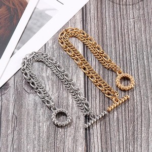 Detailed view of silver and gold chunky chain bracelets with OT toggle closures on wood