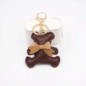 Close-up of dark brown PU leather bear keychain with tan bowtie and gold metal hardware