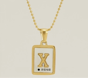 Detail of 18K gold plated stainless steel square pendant with 3D letter X on white inlay