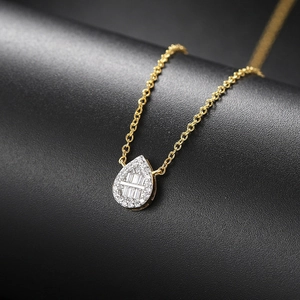 Macro detail of teardrop pendant with baguette-cut crystals and gold chain necklace