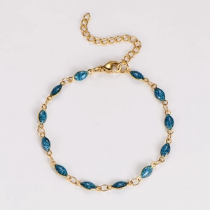 Detailed macro of gold chain bracelet featuring blue glitter marquise-shaped charms