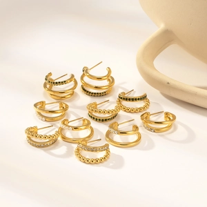 Close-up of 18K gold layered C-shape earrings with green zircon and pearls