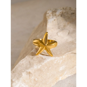 18k gold plated stainless steel starfish ring on a natural beige stone display