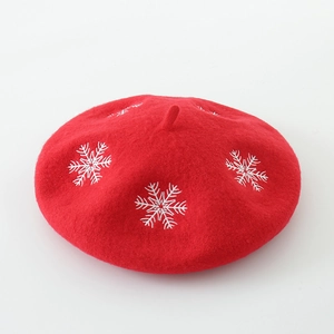 Detailed close-up of red wool felt beret featuring white snowflake embroidery pattern