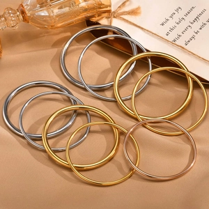 Polished gold, silver, and rose gold stainless steel bracelets on a fabric background