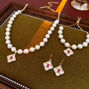Detailed set of gold plated flower charms and pearls on a premium green velvet tray