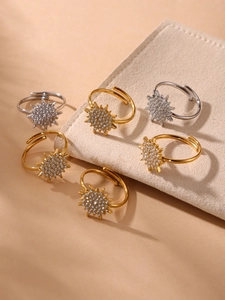 Close-up of gold and silver sunburst rings with sparkling cubic zirconia on a velvet pad