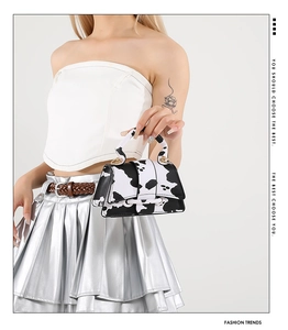 Detail view of mini tote bag featuring chic black and white cow print leather and metal rings
