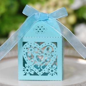 Detail of light blue laser-cut heart favor box with silk ribbon on white plate