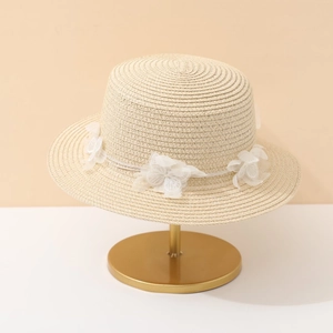 Flat top beige straw sun hat with elegant white lace flower on a display stand