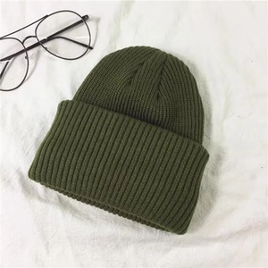 Detailed top-down view of a dark green knitted docker hat on a white textured background