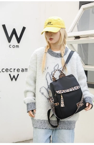 Fashionable black nylon backpack with leopard print trim shown on model for travel