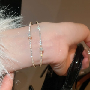 Close-up of double-layer gold bracelets with shimmering zircon pavé and white pearls