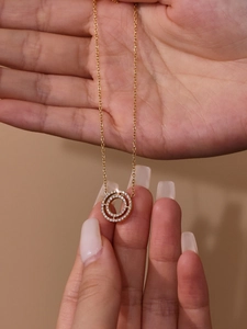 Close-up of golden necklace with double-circle pendant featuring sparkling 5A zircon stones