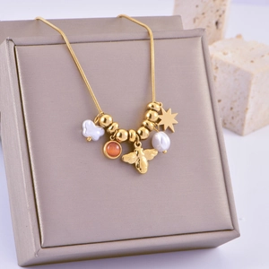 Golden snake chain necklace with bee and pearl pendants on a gray velvet jewelry box