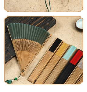 Detailed close-up of a green silk bamboo folding fan with elegant tassel and various colors