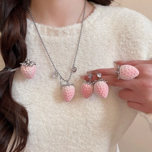Detail of pink strawberry jewelry set including earrings and necklace on model