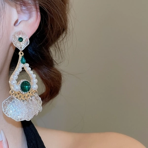 Detailed close-up of vintage emerald and pearl drop earrings with elegant gold hollow work