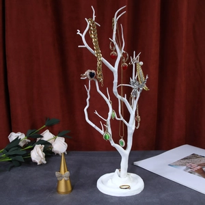 White tree-shaped jewelry organizer stand with various gold necklaces and earrings