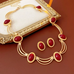 Detailed view of vintage gold necklace and oval red gemstone earrings set on frame