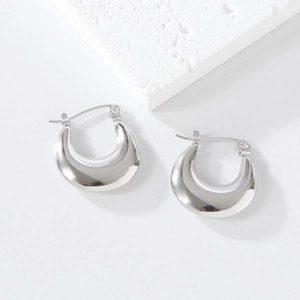 Macro detail of silver irregular thick crescent earrings on a stone texture base