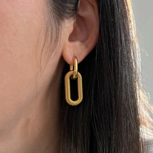 Detail of 18K gold-plated double-loop earrings with textured screw pattern on woman ear