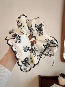 Detail of rose print scrunchie with black lace trim, ribbon bow and pearl charm