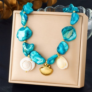 Detail of bohemian gold chain necklace with blue stone beads and white shell pendants