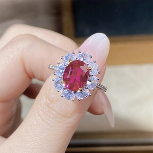 Macro detail of S925 silver ring featuring red oval zircon and clear stones on finger