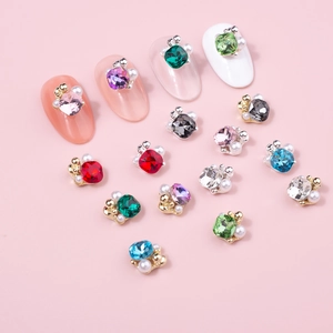 Detailansicht bunter 3D-Nagelkunst-Anhänger mit Goldbasis und Perlen auf zartem Rosa