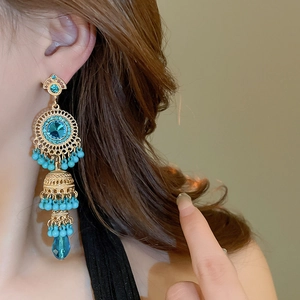 Detail of vintage bohemian tassel earrings with blue gemstones and golden beadwork