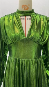 Close-up of metallic emerald green pleated dress with waist cinching and v-neck detail