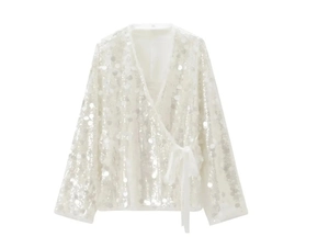 Detailed close-up of silver sequin wrap top with V-neckline and satin tie belt