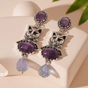 Close-up of vintage cat earrings with purple oval stones and teardrop crystal beads