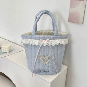 Dettaglio della borsa a righe blu con bordo in pizzo a cuore e ricamo a fiocco rosa