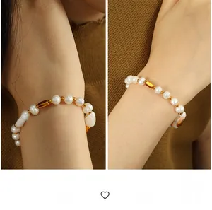 Detail showing white freshwater pearls and gold metal cylinders on the wrist bracelet