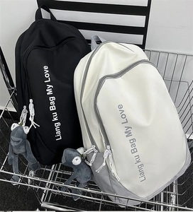 Detail view of large school backpacks in black and white with cute plush frog pendants