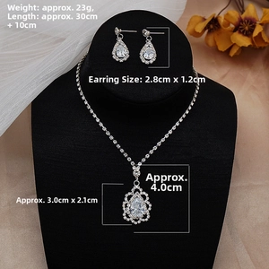 Detailed view of silver zircon drop necklace and earrings set on black jewelry display stand