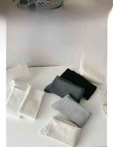 Detailed close-up of rib-knit socks in grey, white, and black neutral color palette