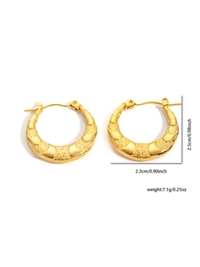 Detailed view of gold earrings showing polished curves and grainy textured surface