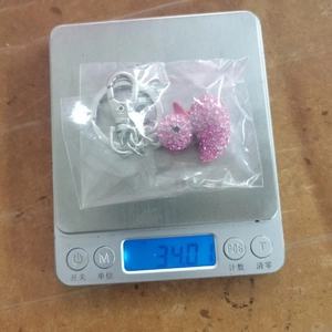 Pink crystal duck keychain with rhinestones shown on scale weighing 34.01g