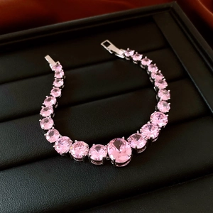 Macro shot of silver bracelet featuring oval and round pink zircons on black leather pad