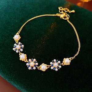 Detail of vintage flower bracelet featuring white pearls and blue zircon on gold chain